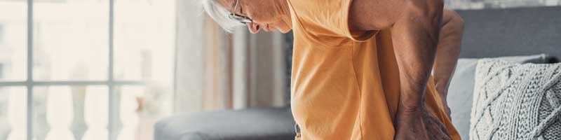 back pain concept - woman holding her aching back